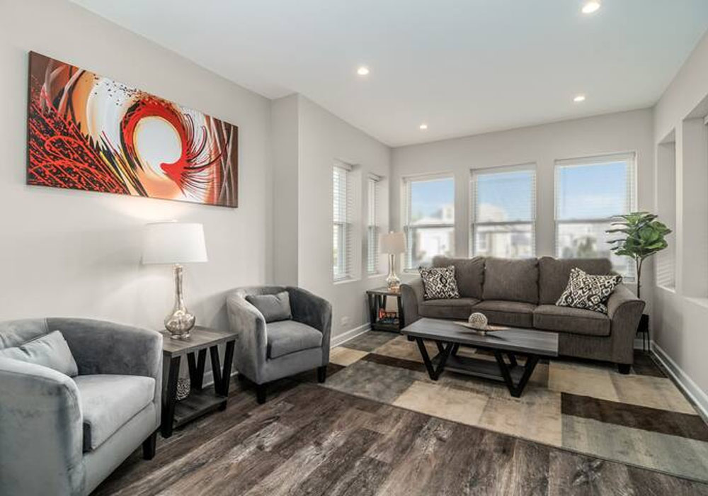 living room area of a corporate housing with two small sofas and large glass windows